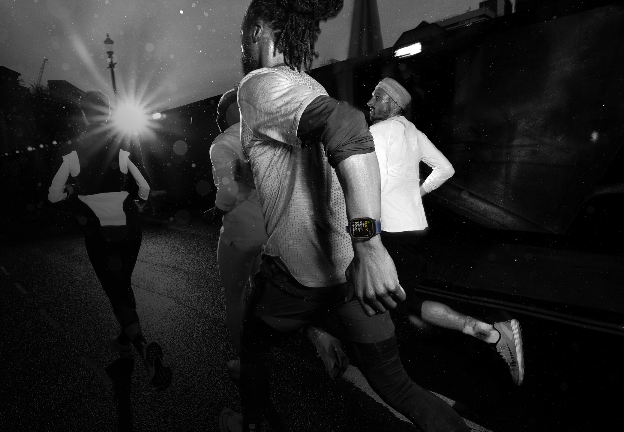 Négy futó városi k?rnyezetben, egyikük Apple?Watch?Ultra?2-t visel.