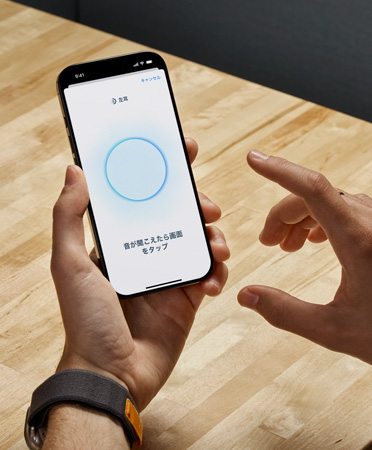AirPods Pro 2のユーザーが、iPhoneを手に持って新しいヒアリングチェック機(jī)能を使っている