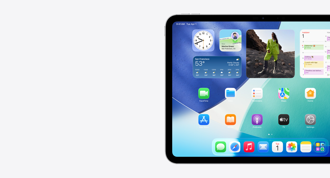 橫向きのiPad。畫面の左側(cè)のみが見えている。Liquid Glassのエフェクトを持つ半透明の時(shí)計(jì)などを含むウィジェットスタック、「探す」アプリ、天気ウィジェット、2列に並んだ小さなアプリ、Dockがホーム畫面に表示されている
