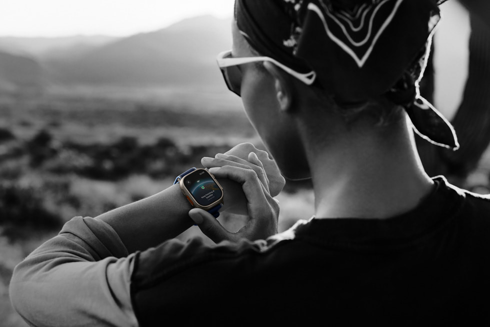 Ein Schwarz-Weiss-Foto einer Person beim Laufen in einer Wüstenlandschaft, die ihre Satellitenverbindung auf der Apple Watch Ultra?3 überprüft.