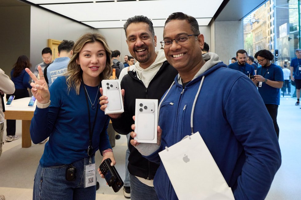 An Apple team member and two customers pose with their iPhone 17 Pro purchases at Apple Sydney in Sydney, Australia.