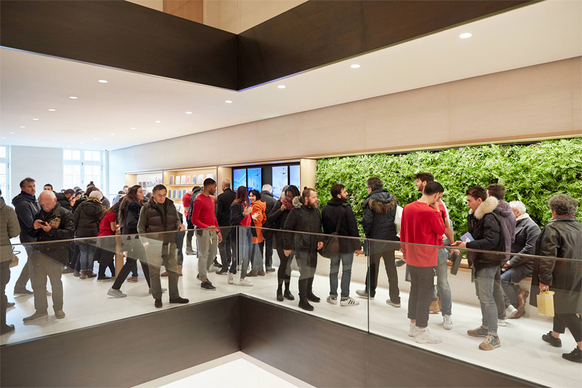 Ekip üyeleri ve mü?teriler Apple Champs-élysées’deki ye?il bir duvar?n ?nünde duruyor.