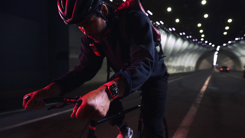 A cyclist wearing Apple?Watch?Series?7 rides through a tunnel at nighttime.