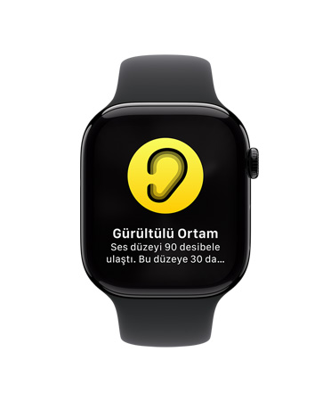 Beyaz Spor Kordonlu Apple Watch Series 10’un ?nden g?rünümü, Kullan?c? Arayüzünde Gürültü Bildirimi simgesi g?rülüyor ve Gürültülü Ortam, ses düzeyi 90 desibele ula?t? yaz?yor.