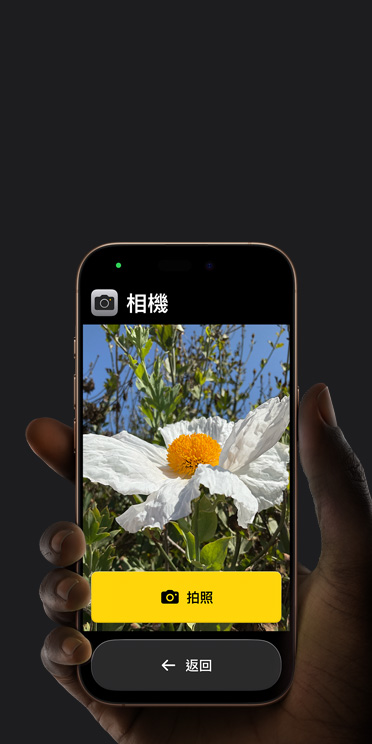 iPhone?16?Pro 螢幕展示簡化的相機 app 介面，取景框中有一朵白色的花和「拍照」按鈕，底下還顯示「返回」按鈕
