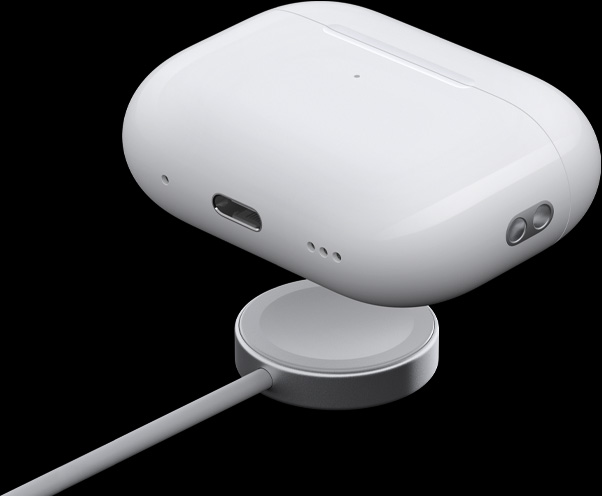 Vista en ángulo 3/4 del estuche de carga MagSafe que resalta el parlante, el pasacorreas y el puerto USB-C, el estuche se está acercando a un cargador de Apple Watch.