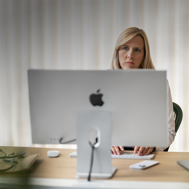 M?t nhan viên y t? nhìn vào màn hình iMac trên bàn làm vi?c.