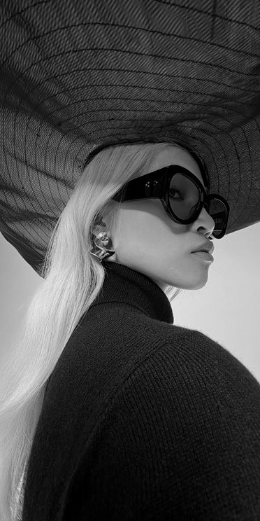 Foto de un primer plano en blanco y negro de una persona con lentes de sol y un sombrero grande