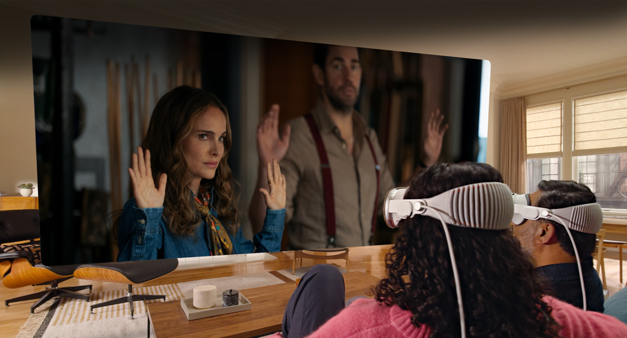 Two people both wearing Apple Vision Pro sit side by side on a couch watching: Fountain of Youth movie, displayed on a screen stretching across the room