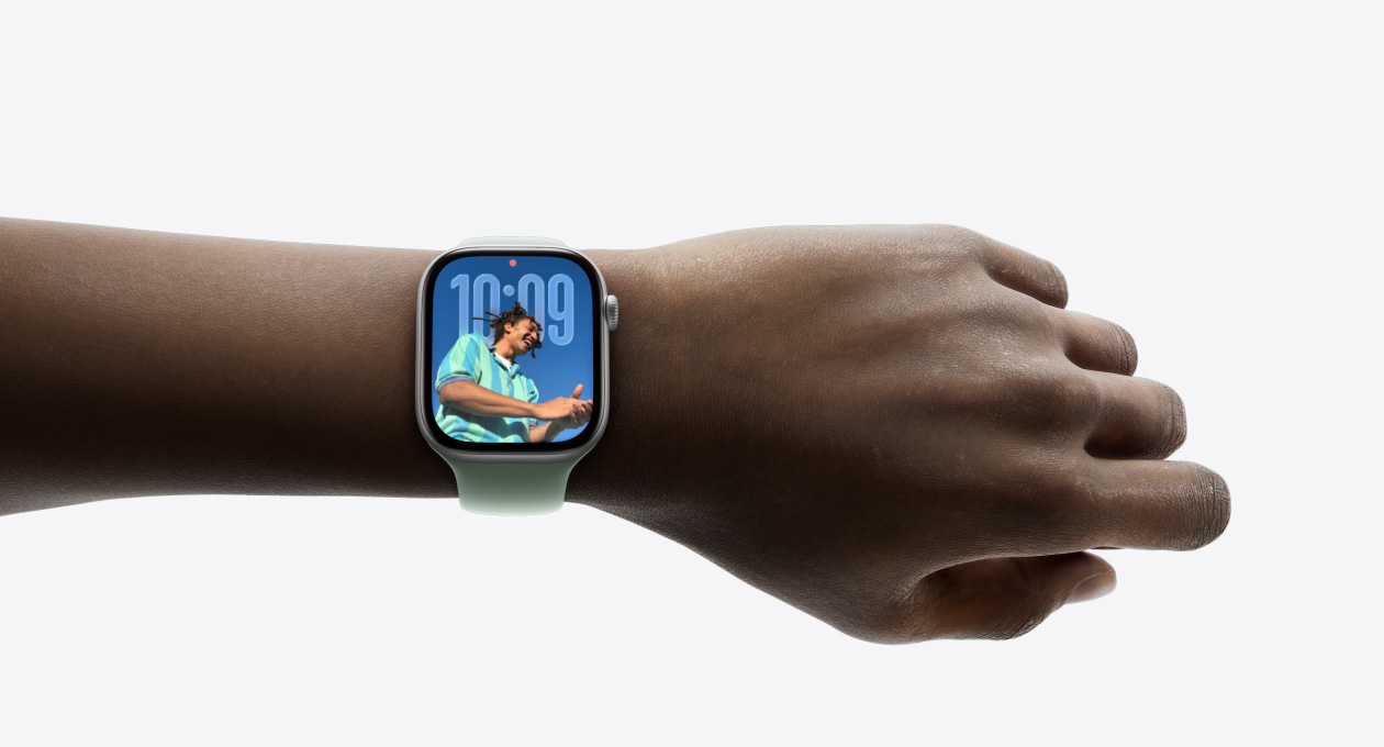 Close-up of Apple Watch in Silver with rubber strap on a person’s wrist, showing new Liquid Glass design