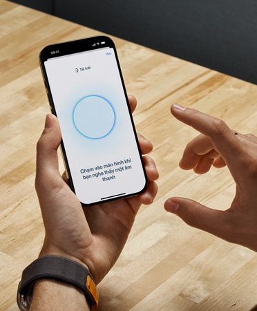 Ng??i dùng AirPods Pro 2 c?m iPhone trong khi s? d?ng tính n?ng Ki?m Tra Thính Giác m?i